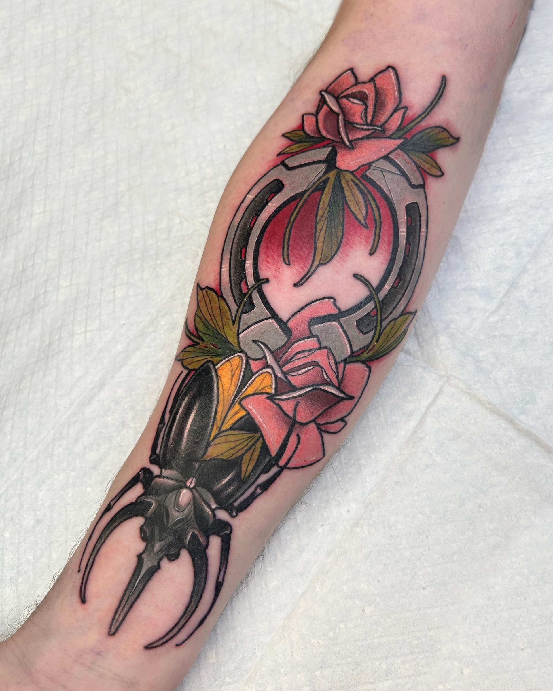 Neo traditional tattoo of a black beetle with red roses and a horseshoe — bold illustrative color design