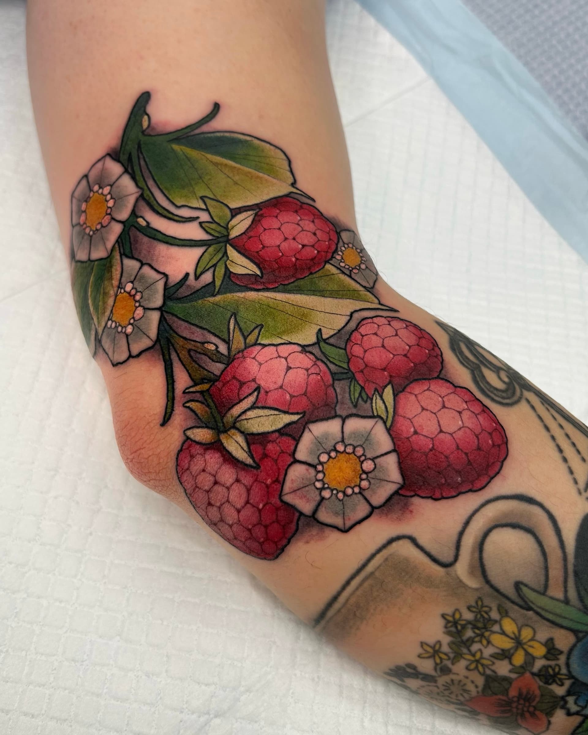 Neo traditional tattoo of raspberries with green leaves and white flowers — vibrant color botanical design