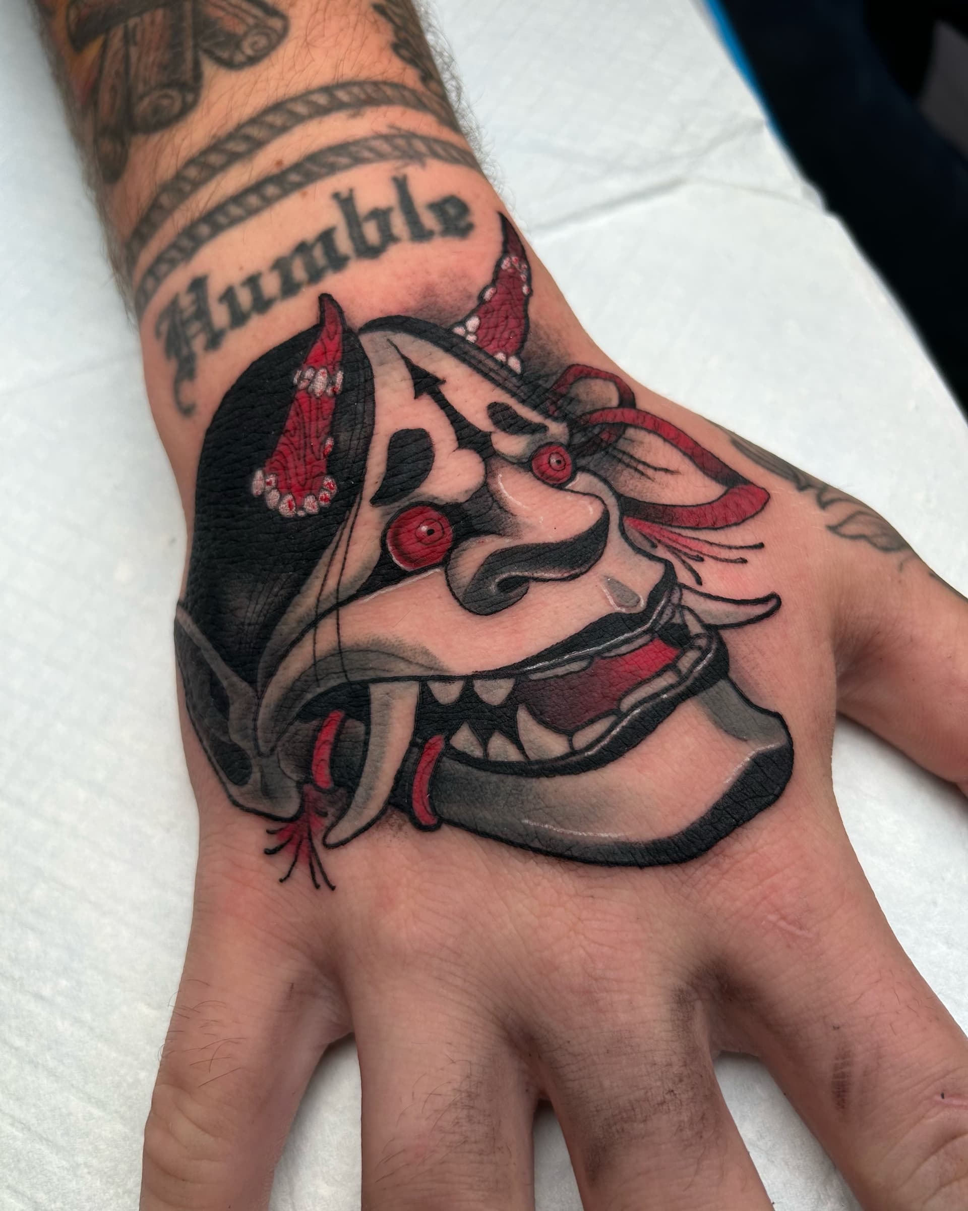 Neo traditional hand tattoo of a red-eyed oni with bold black and red details — Japanese design