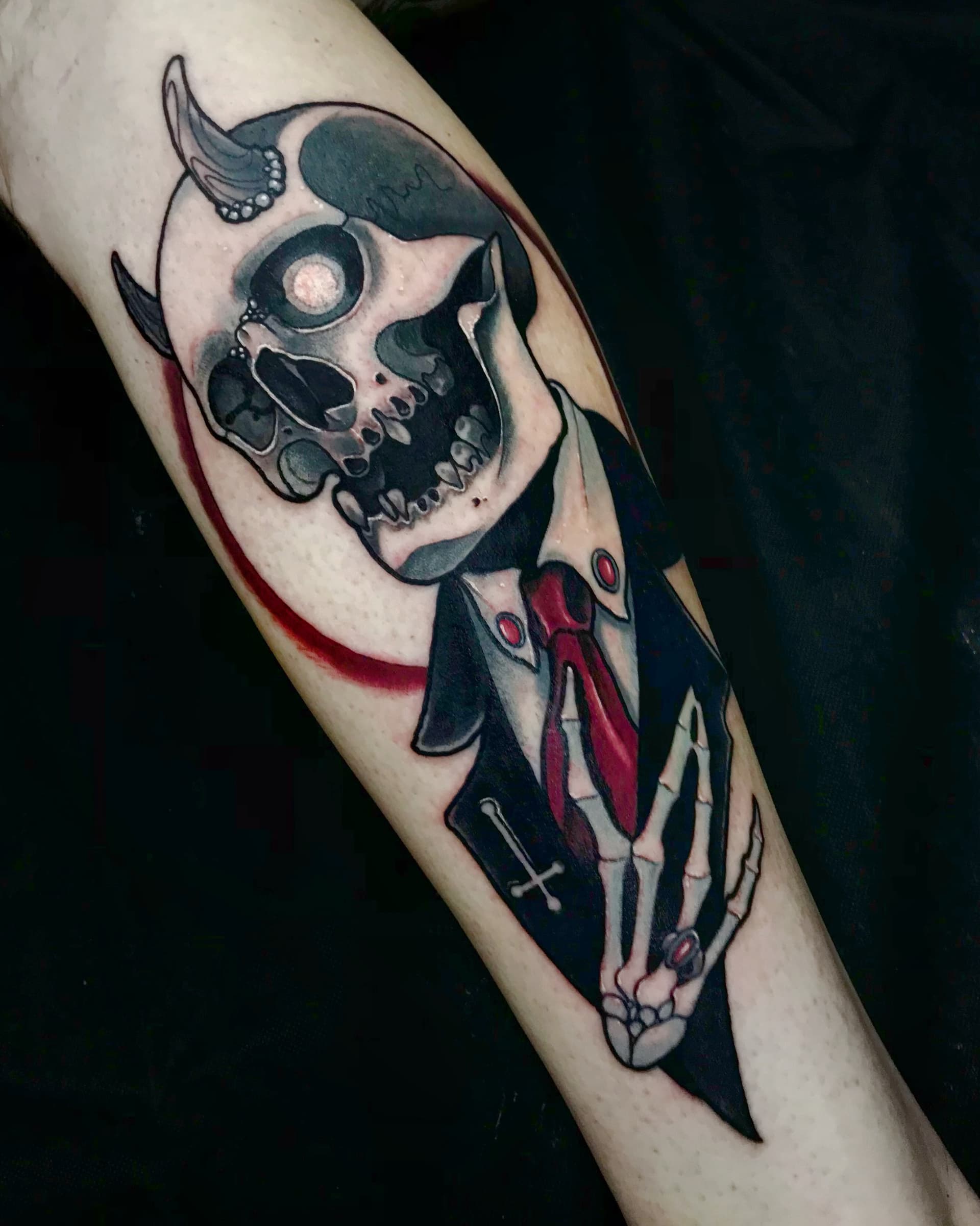 Neo traditional tattoo of a horned skull wearing a suit and red tie — bold dark illustrative design